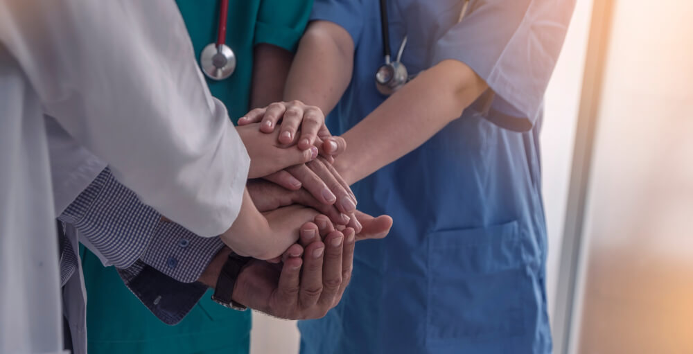 Group of doctors with all hands in a circle